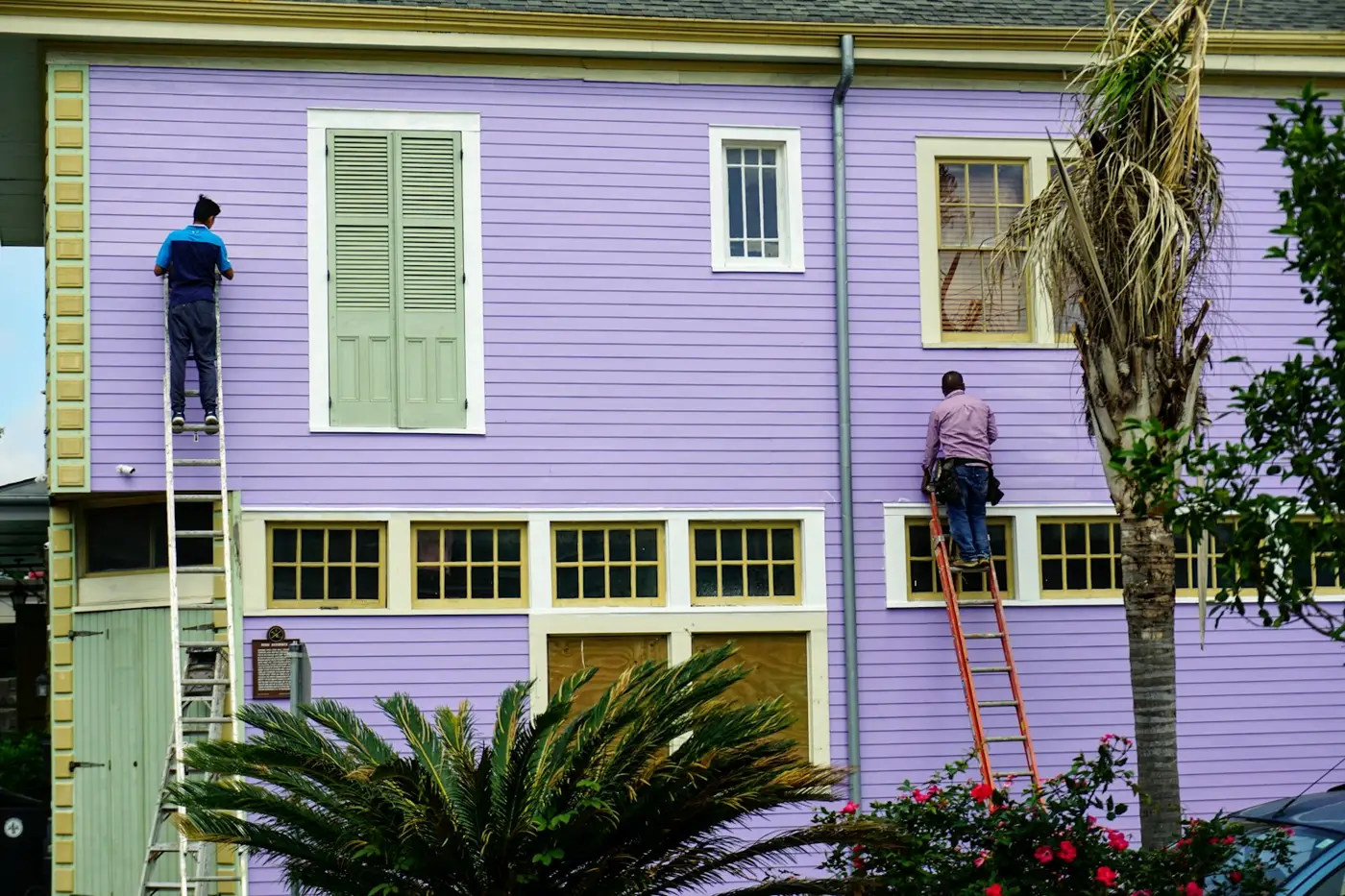 Painters on ladders repainting a weatherboard house